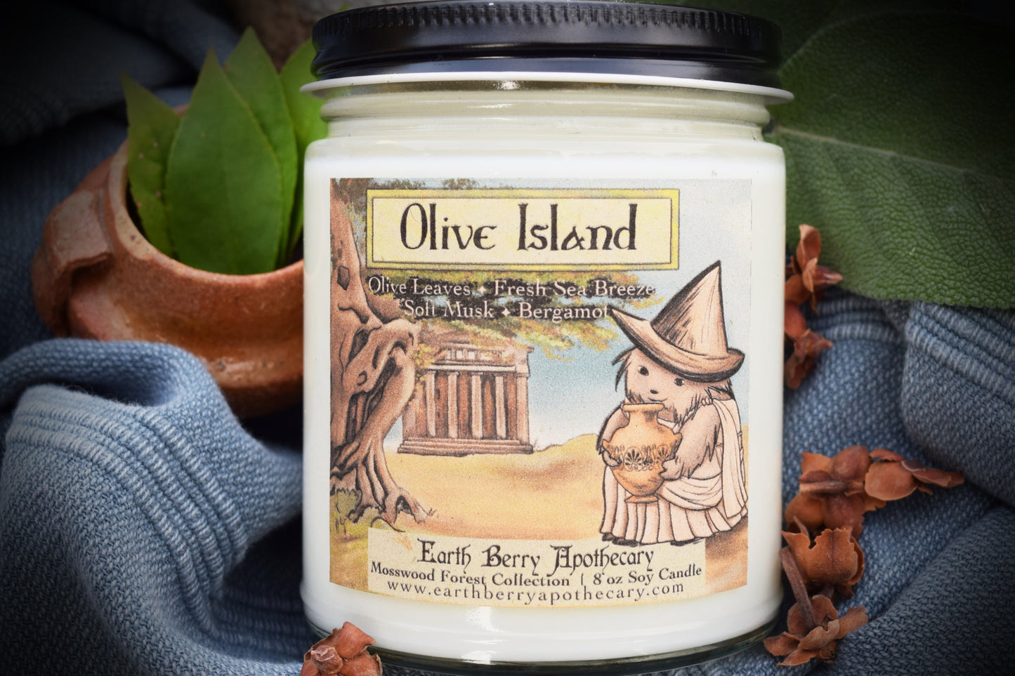 Greek and Roman inspired mythology themed soy candle. Olive island has the temple and olive tree with a hedge witch hedgehog holding an ancient urn.