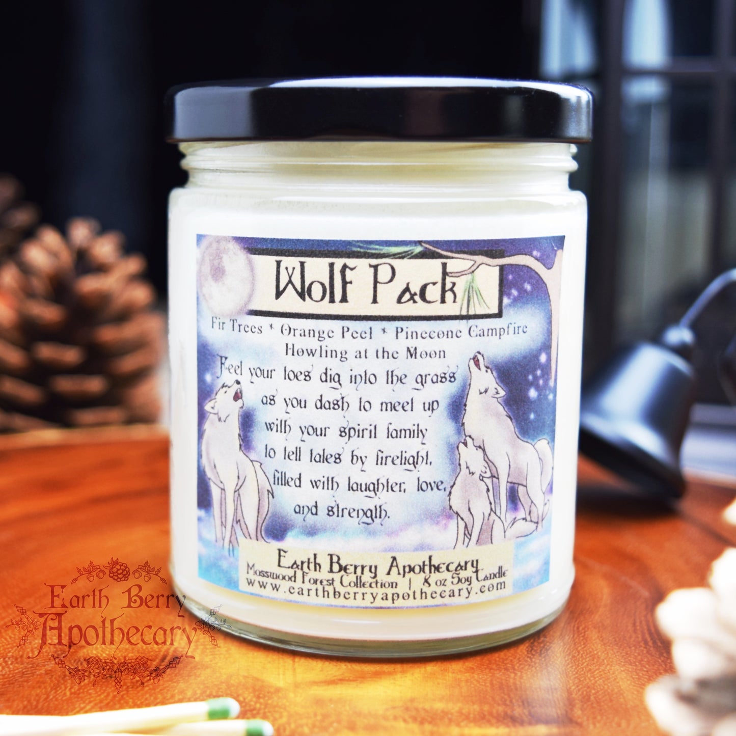 Fantasy nature candle called wolf pack with orange citrus and woodsmoke scent. The label features 3 wolves howling at the moon.